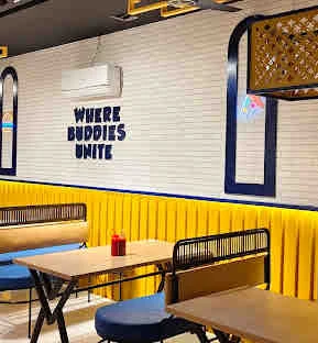 MDee's vibrant dining area with Where Buddies Unite wall